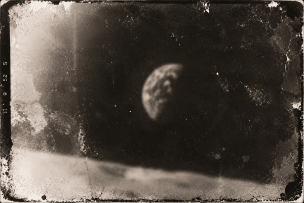 Damaged film frame: the Earth above the lunar horizon, the image soft and chemically blotched