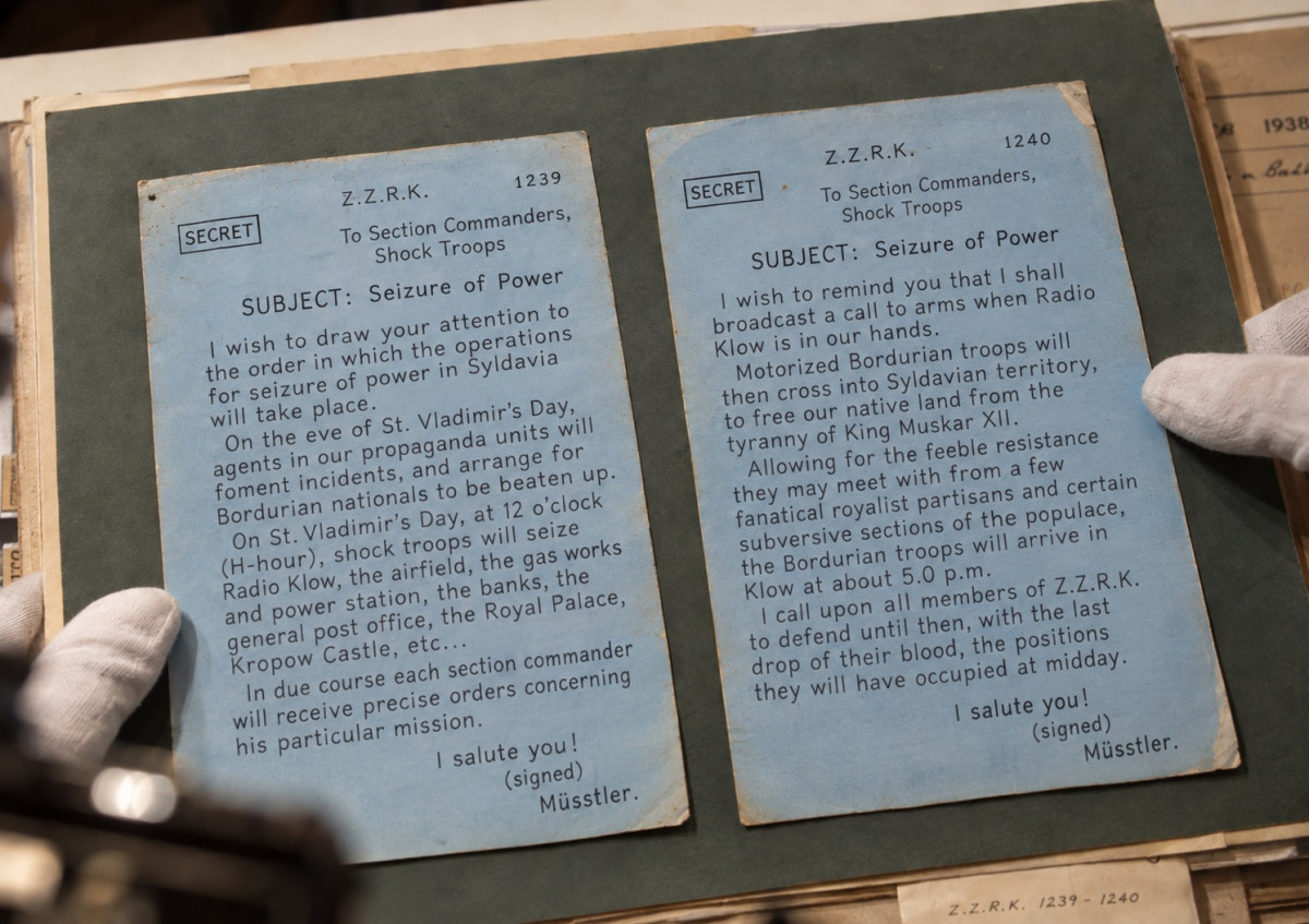 Two typed blue cards held in white-gloved hands on the mount of an archive file labelled Z.Z.R.K. 1239-1240: the secret orders 1239 and 1240, in English, headed Seizure of Power and addressed to the section commanders of the shock troops, each signed Müsstler