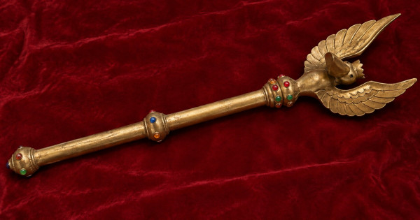 The Sceptre of Ottokar on crimson velvet: a gold rod with four collars set with red, blue, green and orange stones, topped by a crowned pelican with raised wings