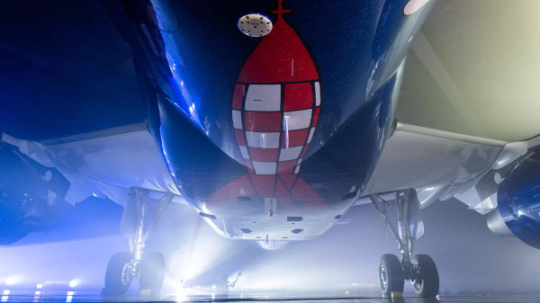 Underside of a Brussels Airlines aircraft in a misty hangar, its belly painted with the red-and-white chequered lunar rocket