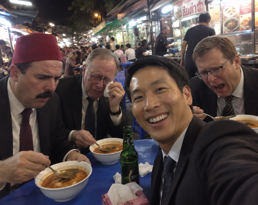 Four colleagues eating tom yum kung at a Yaowarat street stall, three of them in tears from the chilli